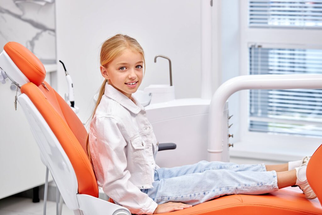 portrait of little cute caucasian child girl in cabinet of dentist. treatment, medicine, hospital. adorbale pretty blonde kid looking at camera