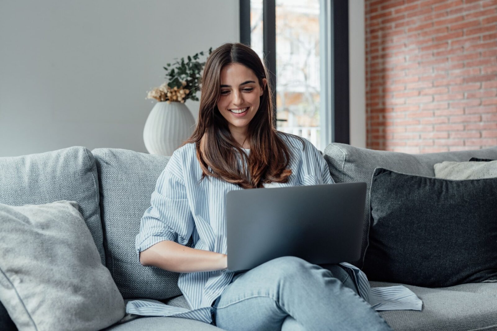 Concentrated girl sit on couch working on laptop