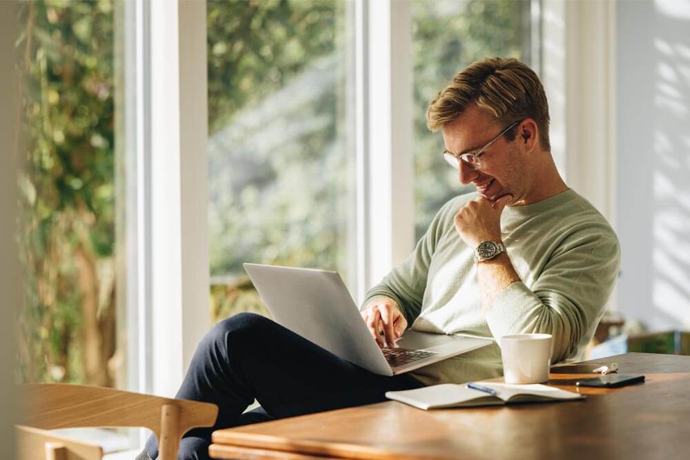 Young man using laptop and smiling at home