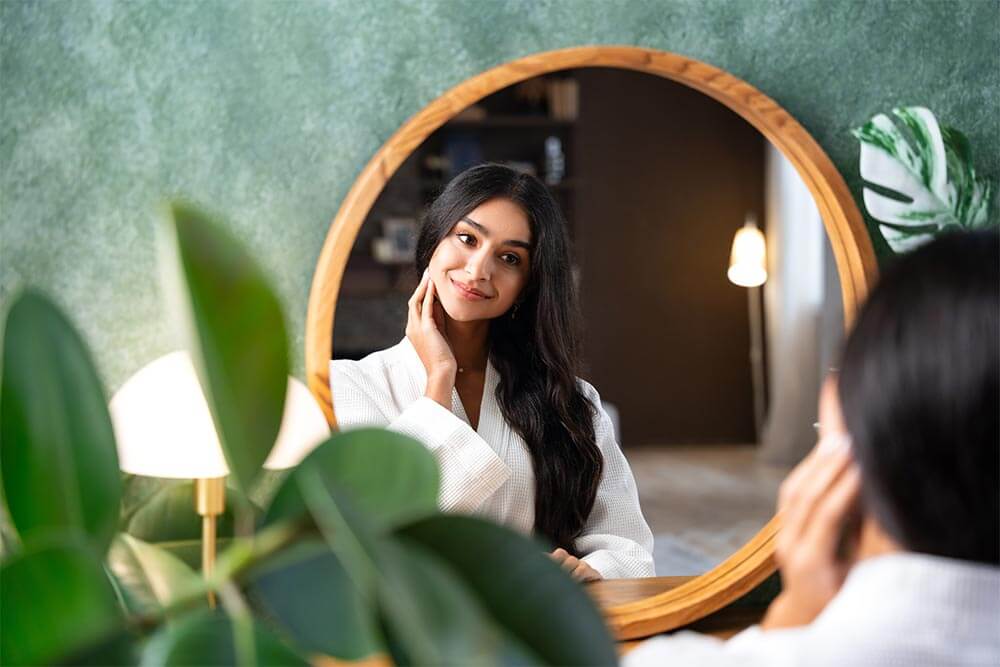 beautiful woman looking in mirror touching her healthy long hair