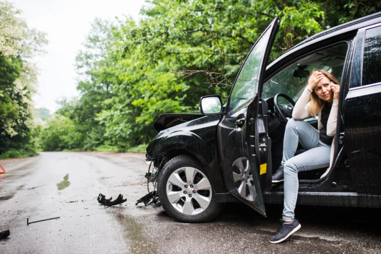 Young woman in the damaged car after a car accident