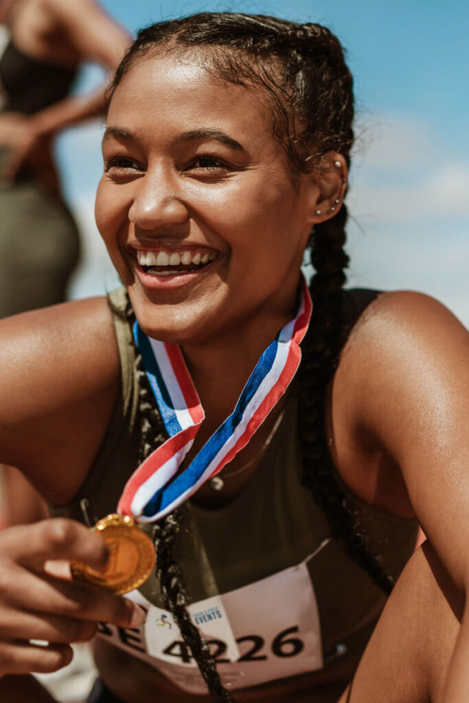 Female runner with a gold medal sitting on track