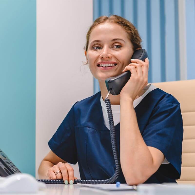 Smiling young woman receptionist talking on phone