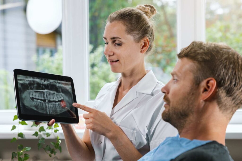 dentist showing teeth x-ray to patient