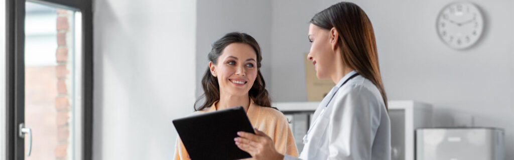 Female doctor with tablet computer talking to smiling female patient