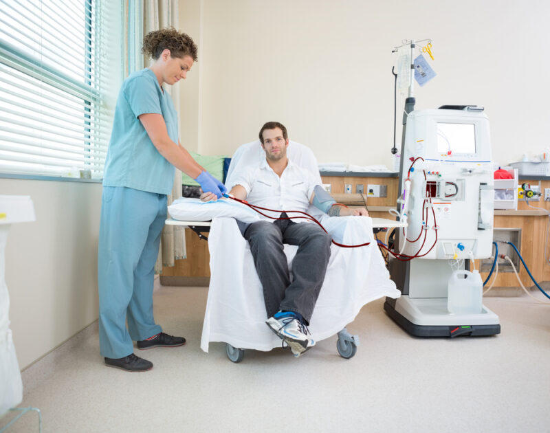 Portrait of male patient being prepared by nurse before renal dialysis in hospital room