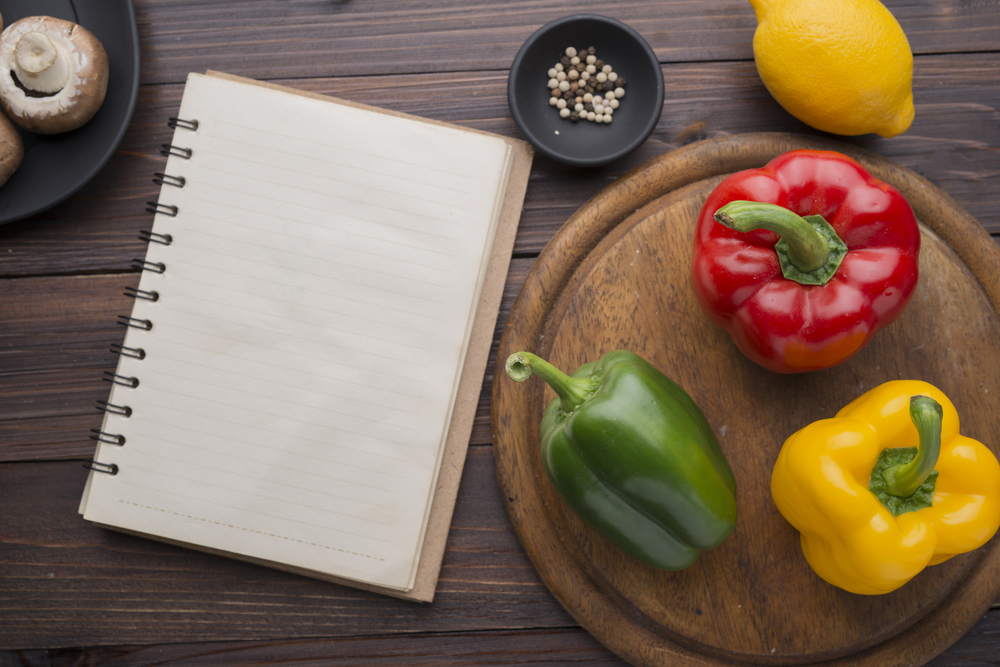 Close up board cooking wood more vegetable ingredients, and old notepad with recipes