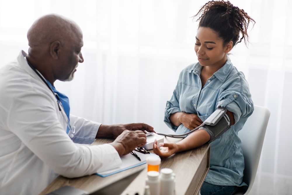 Gestational Hypertension. Mature Male Medical Worker Measuring Arterial Blood Pressure Of Pregnant Black Woman