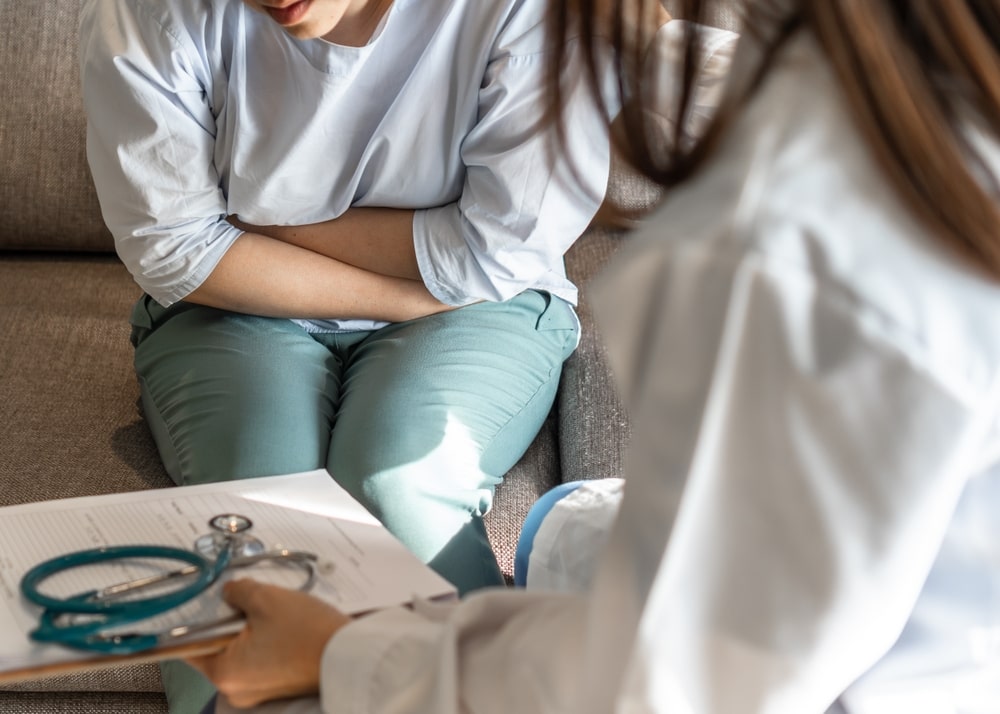 Abdominal pain patient woman having medical exam with doctor on illness from stomach cancer, irritable bowel syndrome, pelvic discomfort