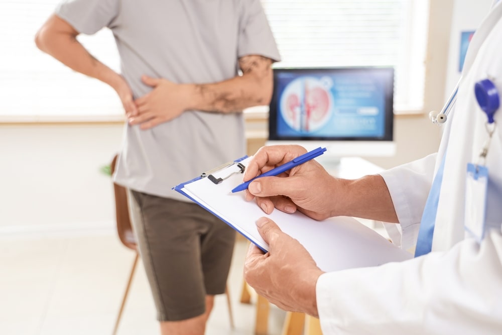 Mature urologist writing on clipboard in clinic, closeup