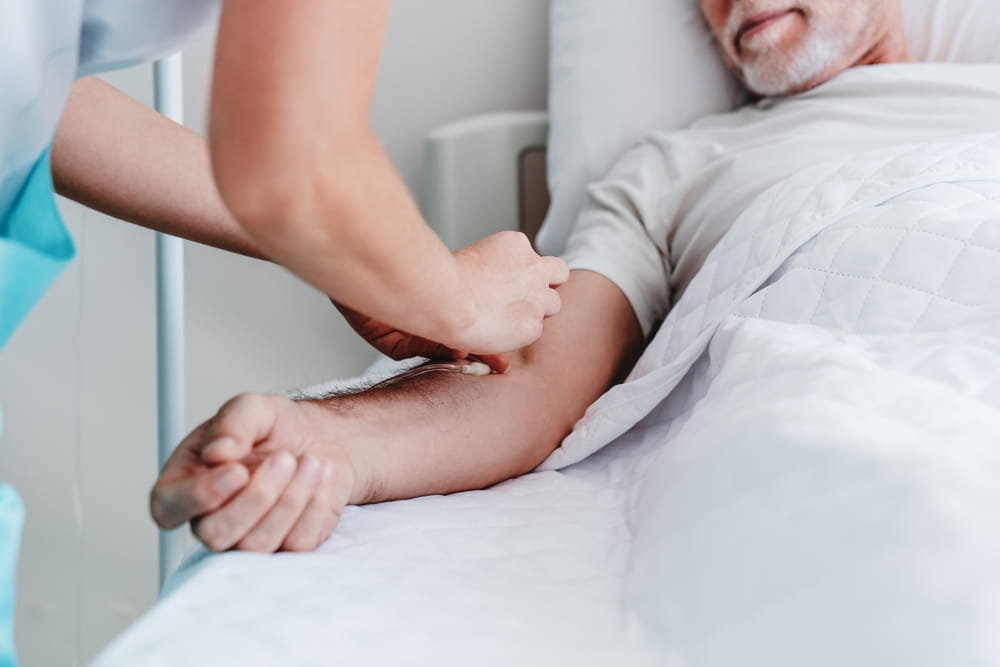 Caucasian nurse putting dropper to ill male patient in hospital bed