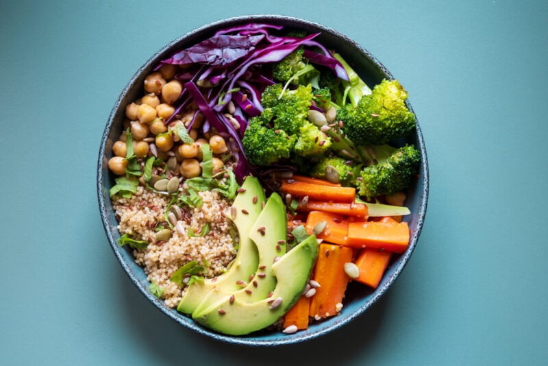 A vibrant vegan quinoa bowl with creamy avocado, protein-packed chickpeas, fresh broccoli, sweet carrots, and crisp red cabbage