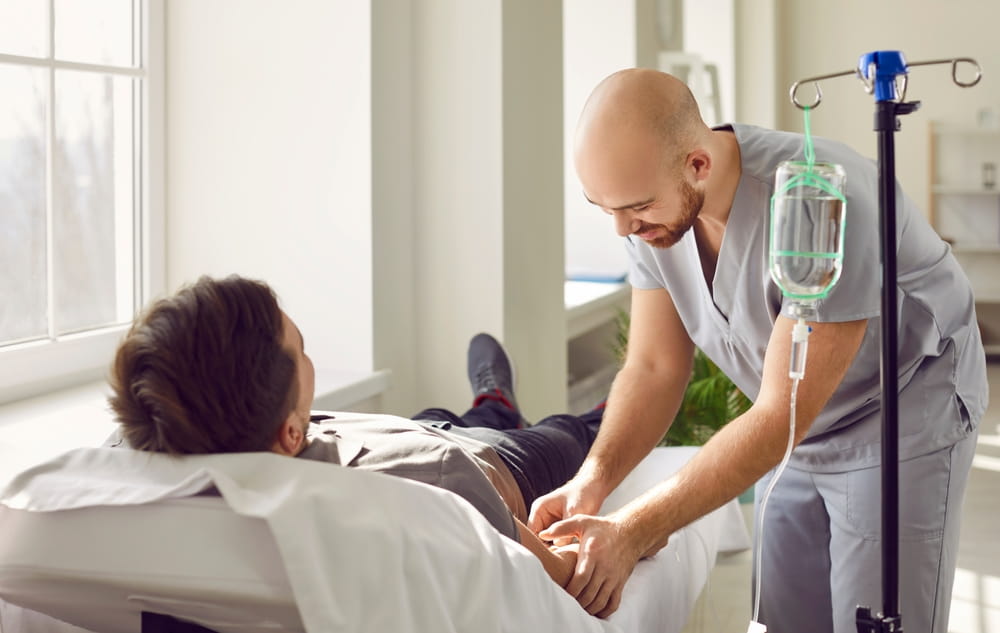 Nursing staff at clinic or hospital gives intravenous vitamin drip or medicine infusion to patient.