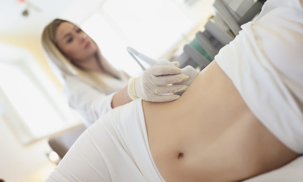 Doctor doing ultrasound examination of kidneys to woman patient in clinic closeup.