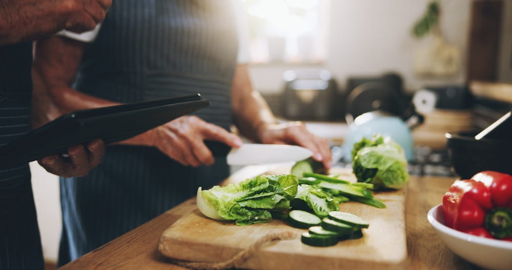 Hands, tablet and salad recipe in kitchen with help, support and teaching at home for healthy food.