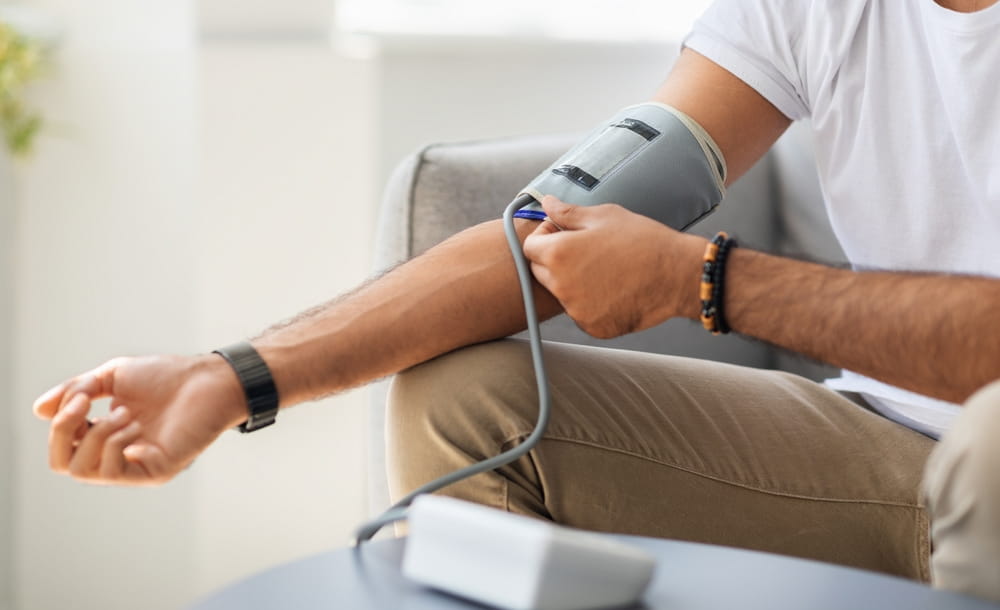 Closeup of unrecognizable male patient using modern tonometer at home, panorama with copy space