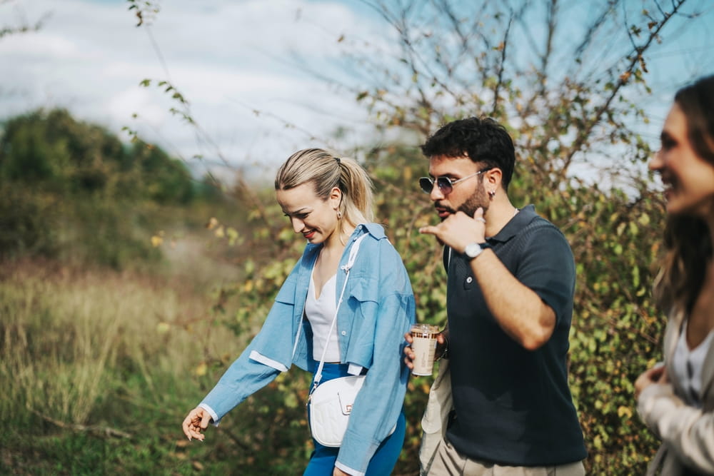 A group of friends walks together, enjoying a leisurely day in nature. They appear happy and relaxed, sharing a casual, outdoors experience.