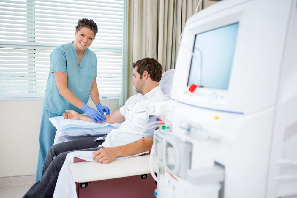 Female nurse hooking male patient up to dialysis machine