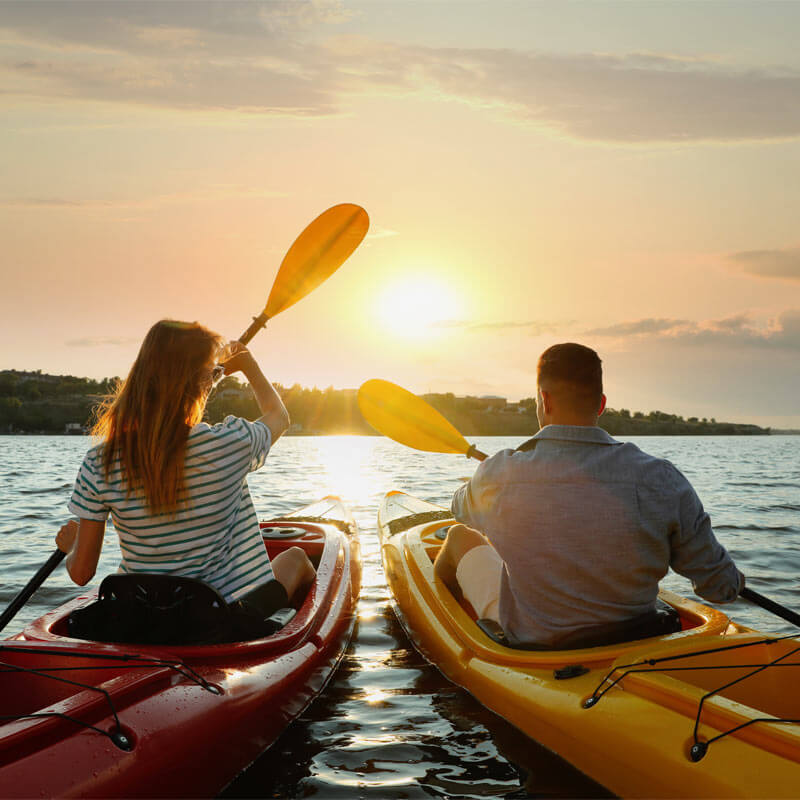 Couple kayaking on river at sunset