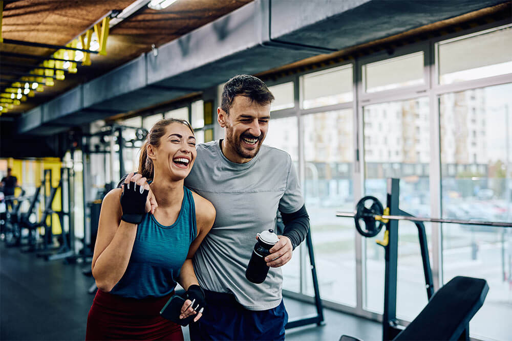 Happy athletic couple laughing while walking through the gym