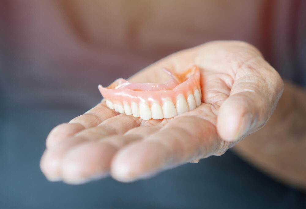 elderly woman holding dentures