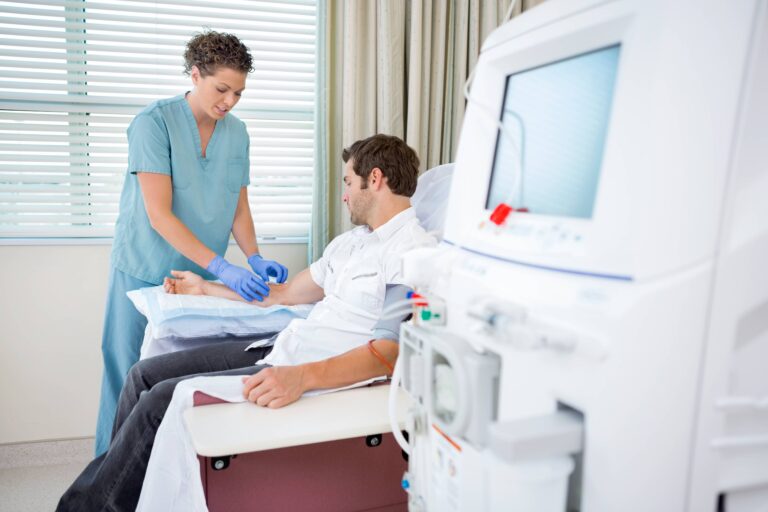 Mid adult female nurse injecting patient for renal dialysis treatment in hospital room