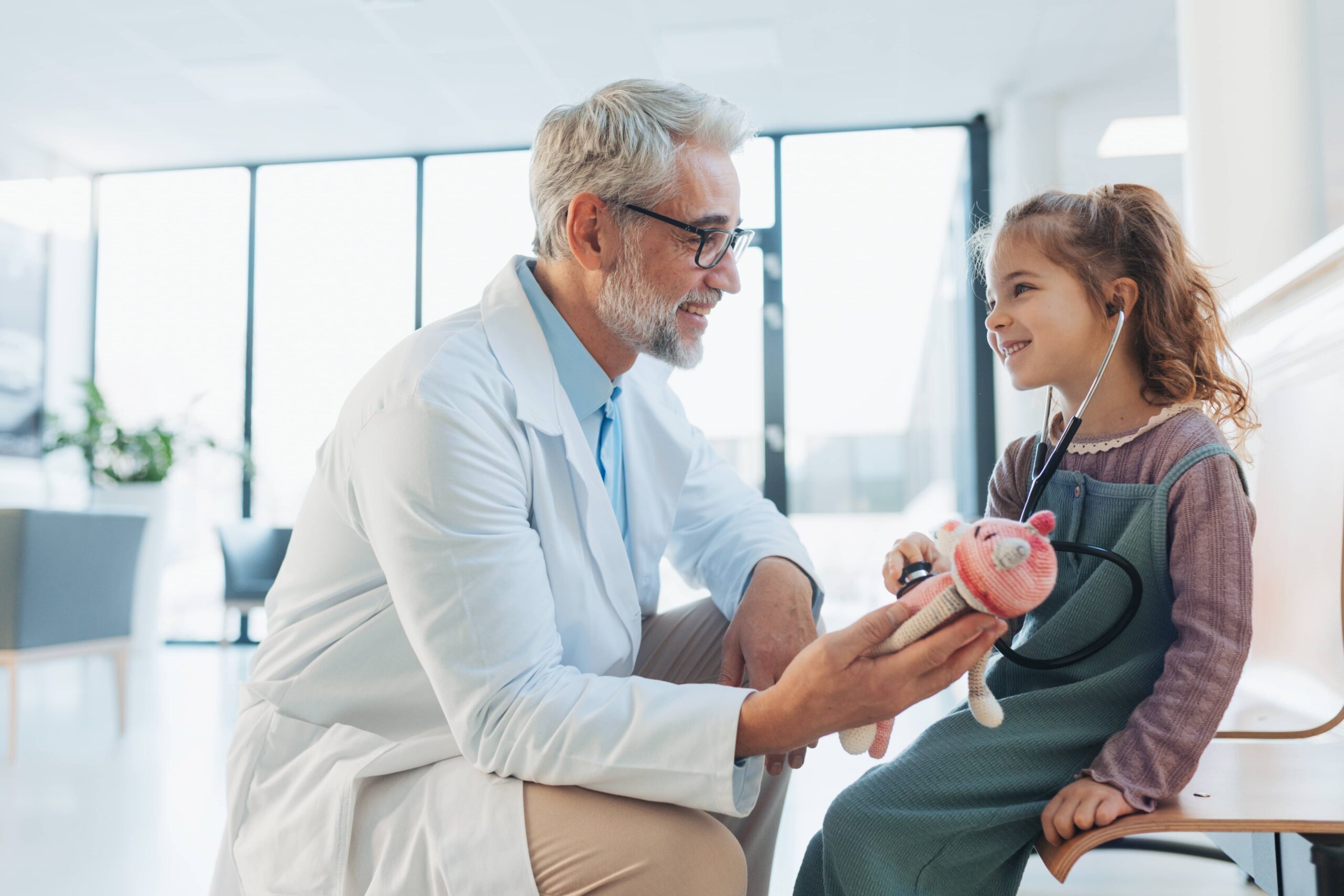 Little girl listening to the plush toy's heartbeat with stethoscope. Role reversal.