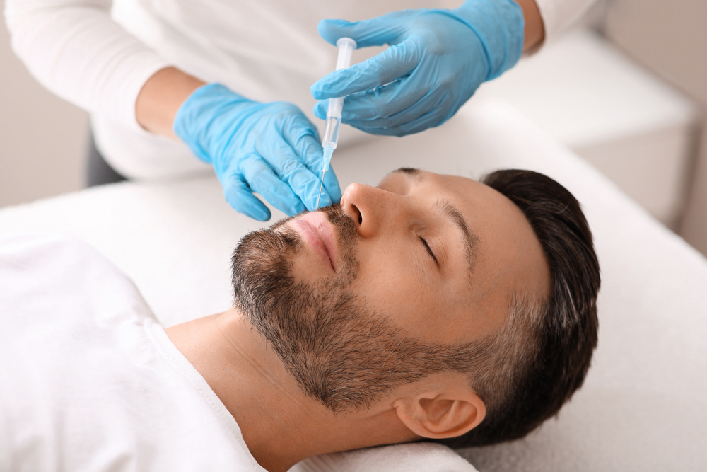 Attractive caucasian bearded man visiting aesthetic clinic, getting lips filler, closeup