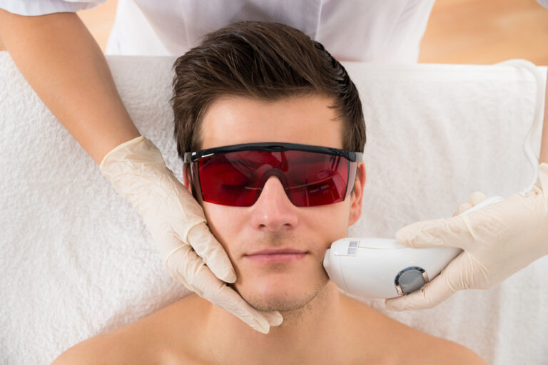 Close-up Of Beautician Giving Laser Epilation Treatment To Young Man Face
