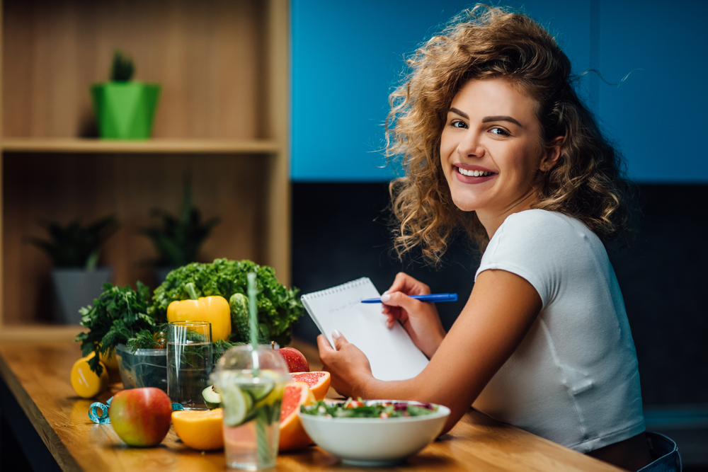 Nutritionist doctor writing diet plan on table