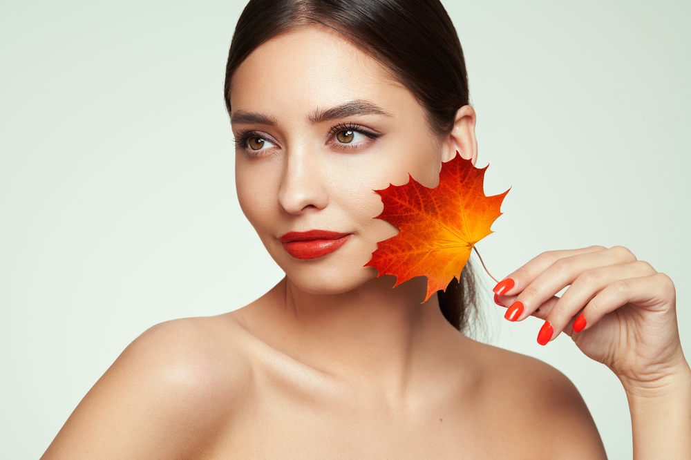 Portrait of beautiful young woman with autumn leaves