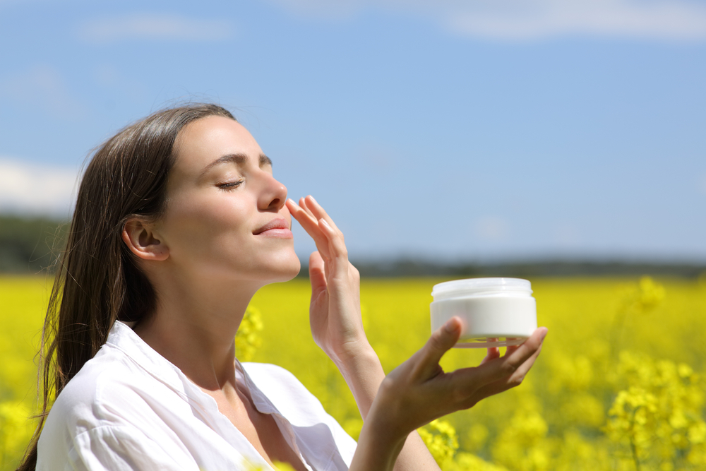 young beautiful woman applying facial cream to face
