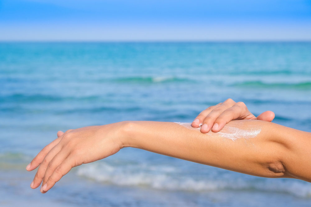 Woman applying sunscreen and taking care of her skin to protect her skin from UV rays