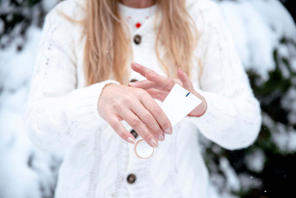 woman applying cream to her dry hands during the winter