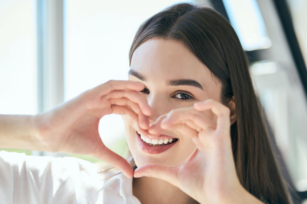 Young Woman Smiling Forming Heart With Hands