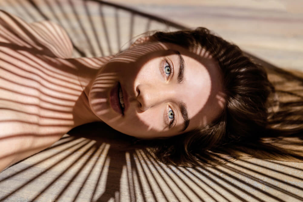 beautiful woman with shadows of palm leaf on her face