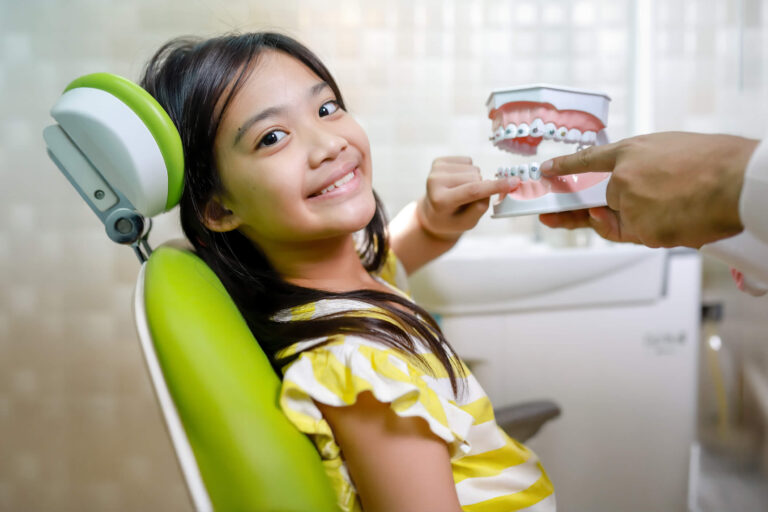 little girl and dentist pointing on orthodontic model