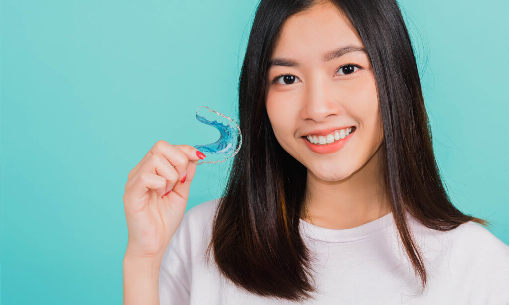 asian teenage girl holding dental aligners