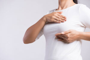 Woman hand checking lumps on her breast for signs of breast cancer