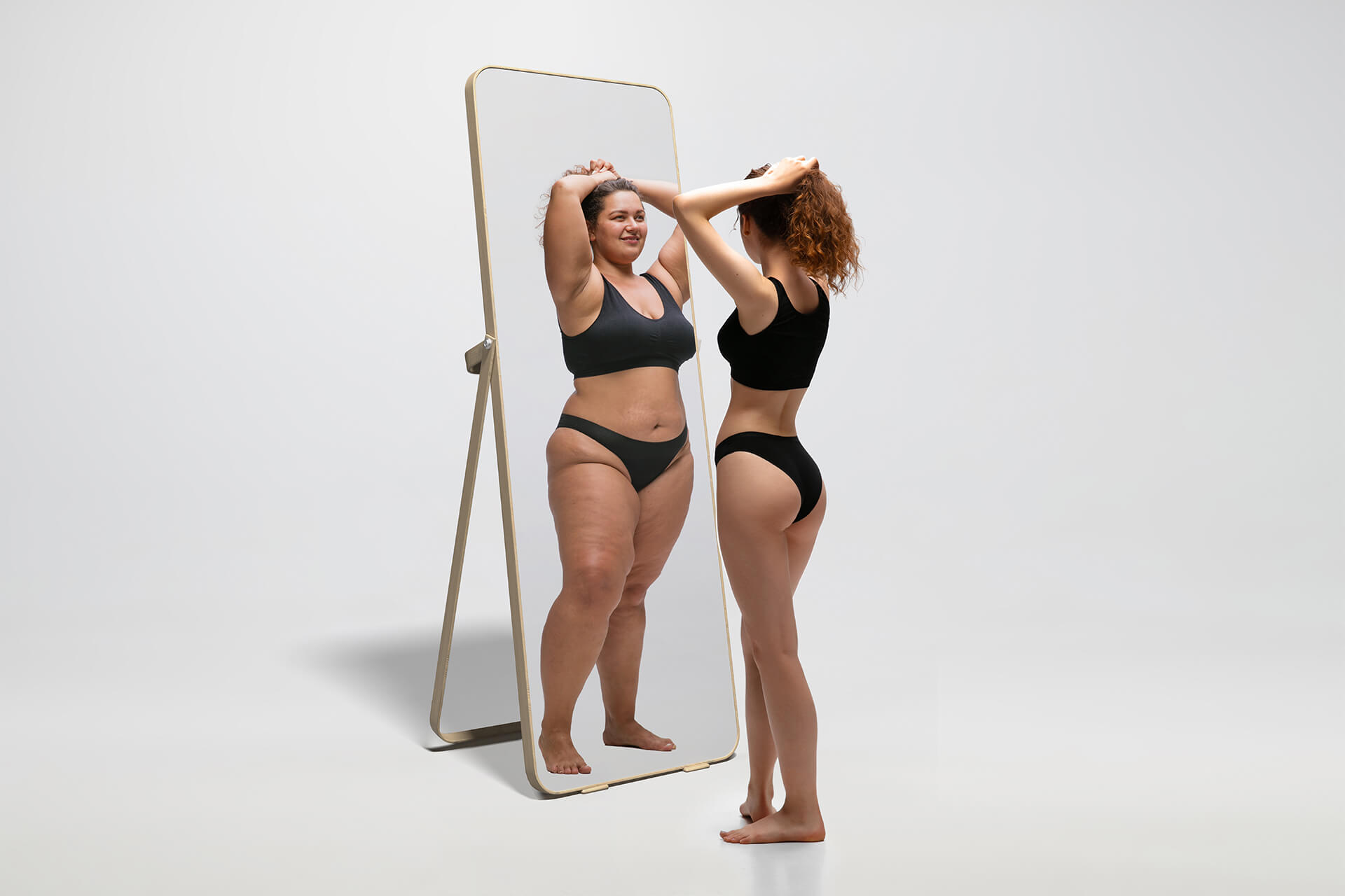 Young fit, slim woman looking at fat girl in mirror's reflection