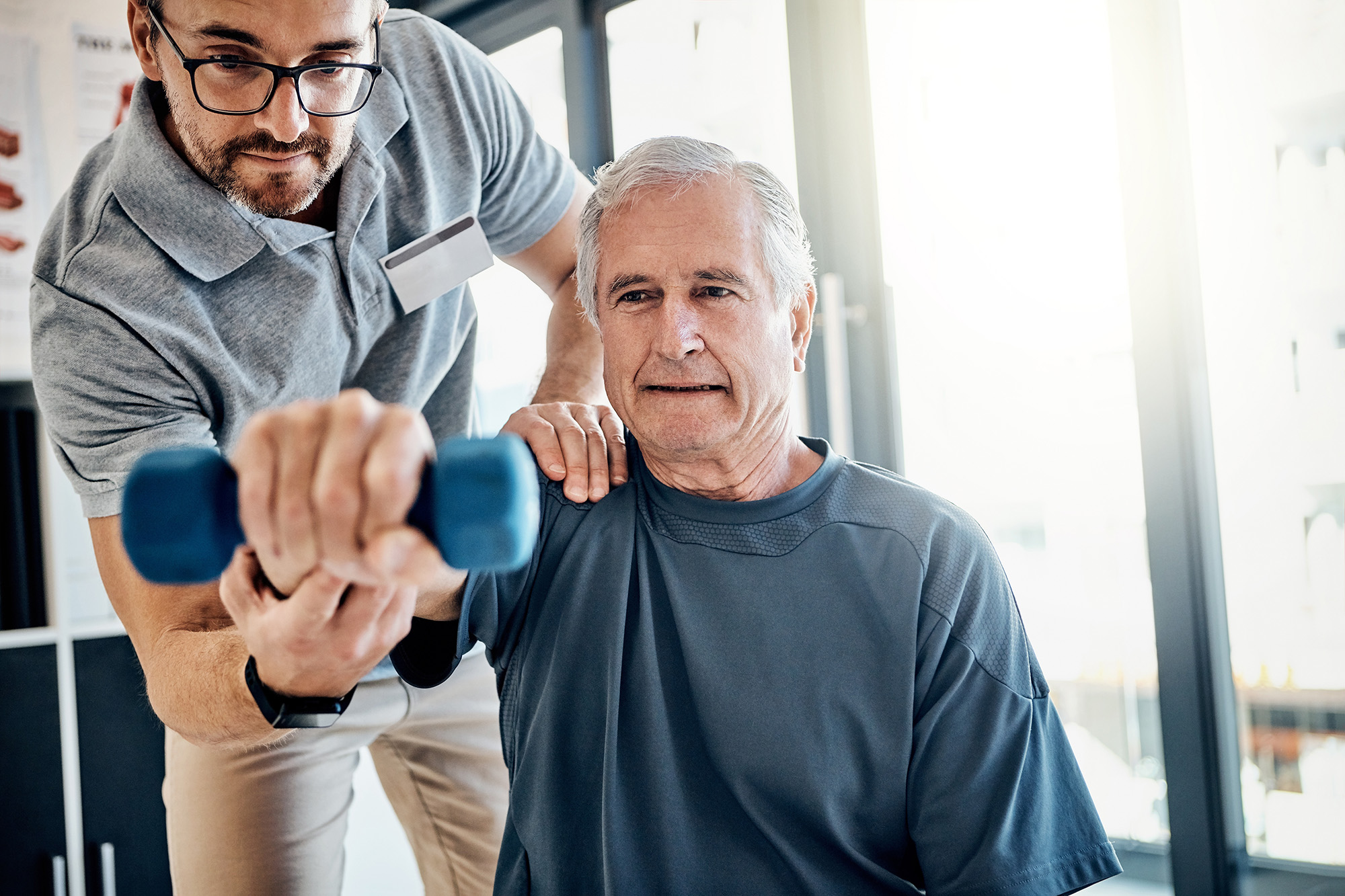 Weight, senior man and physiotherapy with clinic therapist, wellness and client assessment with dumbbell. Consultation, rehabilitation and arm exercise from physical therapy and recovery of patient