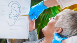 Patient learning about ear points in auriculotherapy treatment.