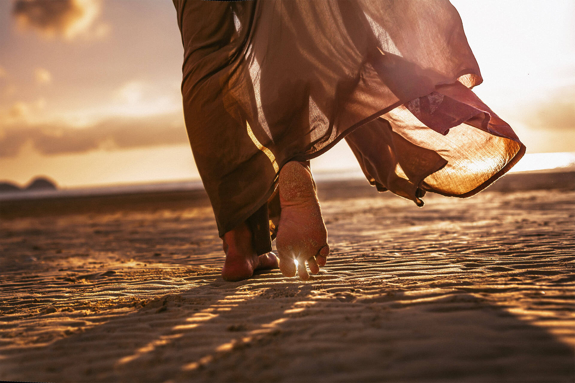 Woman feet walking on the beach at sunset