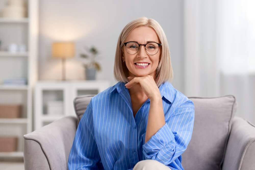 Smiling middle aged woman sitting on armchair