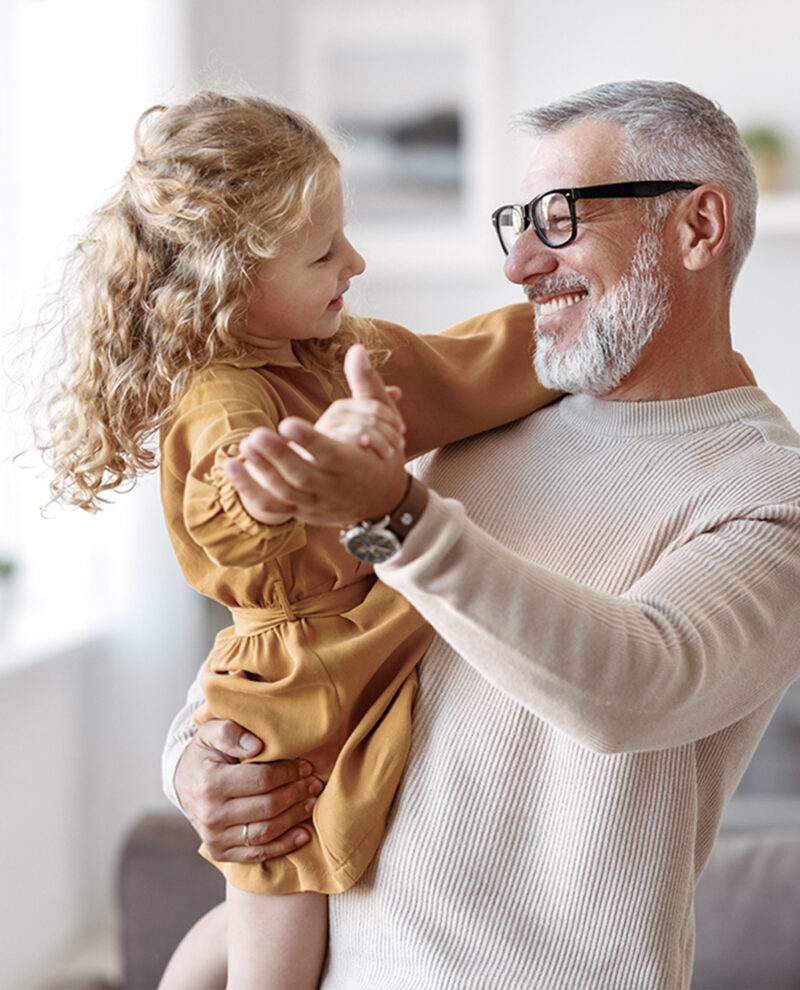 Elegant loving caring grandfather looking at his cute little granddaughter