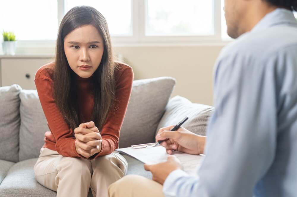 Psychology, depression. Suffer asian young woman consultation with psychologist while patient counseling mental therapy, doctor hand taking notes at clinic