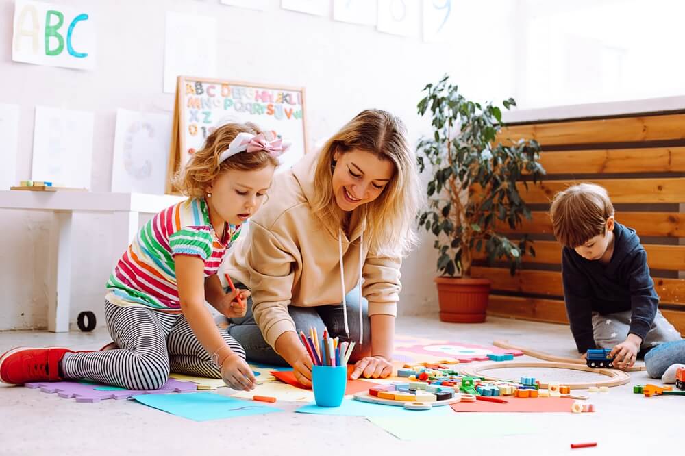 Smiling female psychologist play and test children, make crafts, handmade toys and arts in kid development center for pre schoolers.