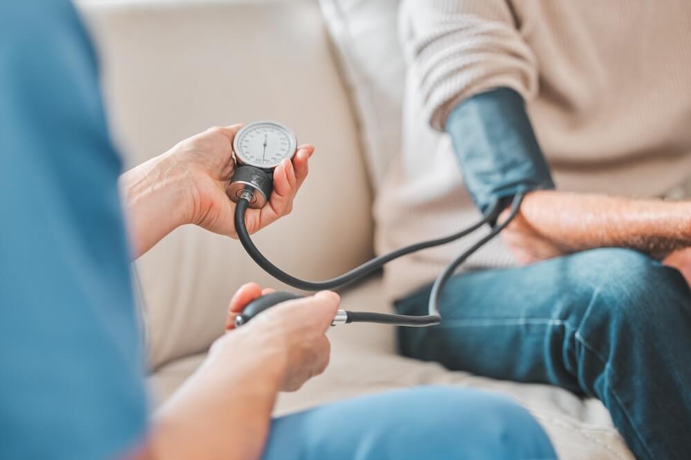 Nurse, elderly patient and blood pressure in house, retirement home and check up with medical professional