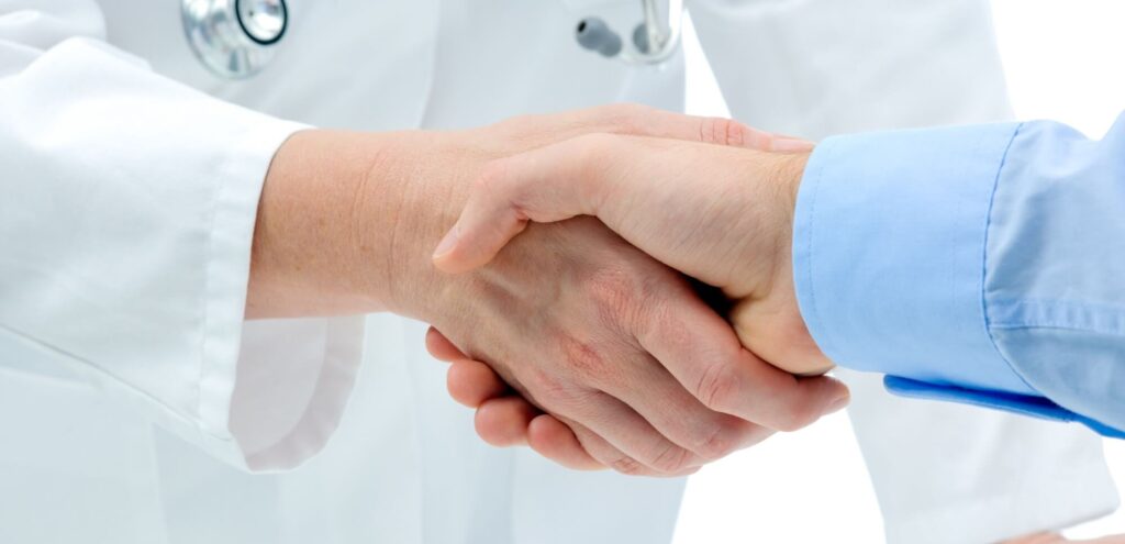 Doctor shakes hands with a patient isolated on white background