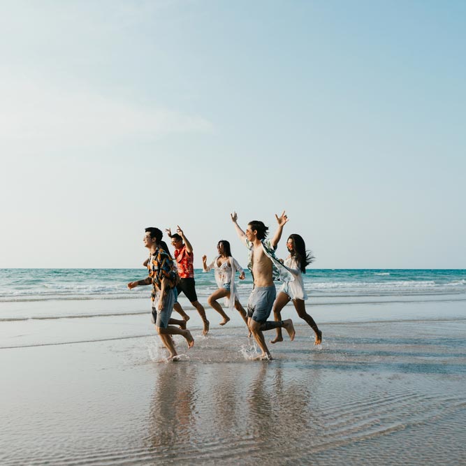 Group of friends running on the beach mo